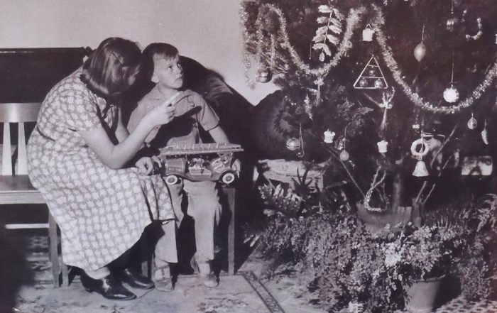 Mother and child sitting on bench by christmas tree in their family home